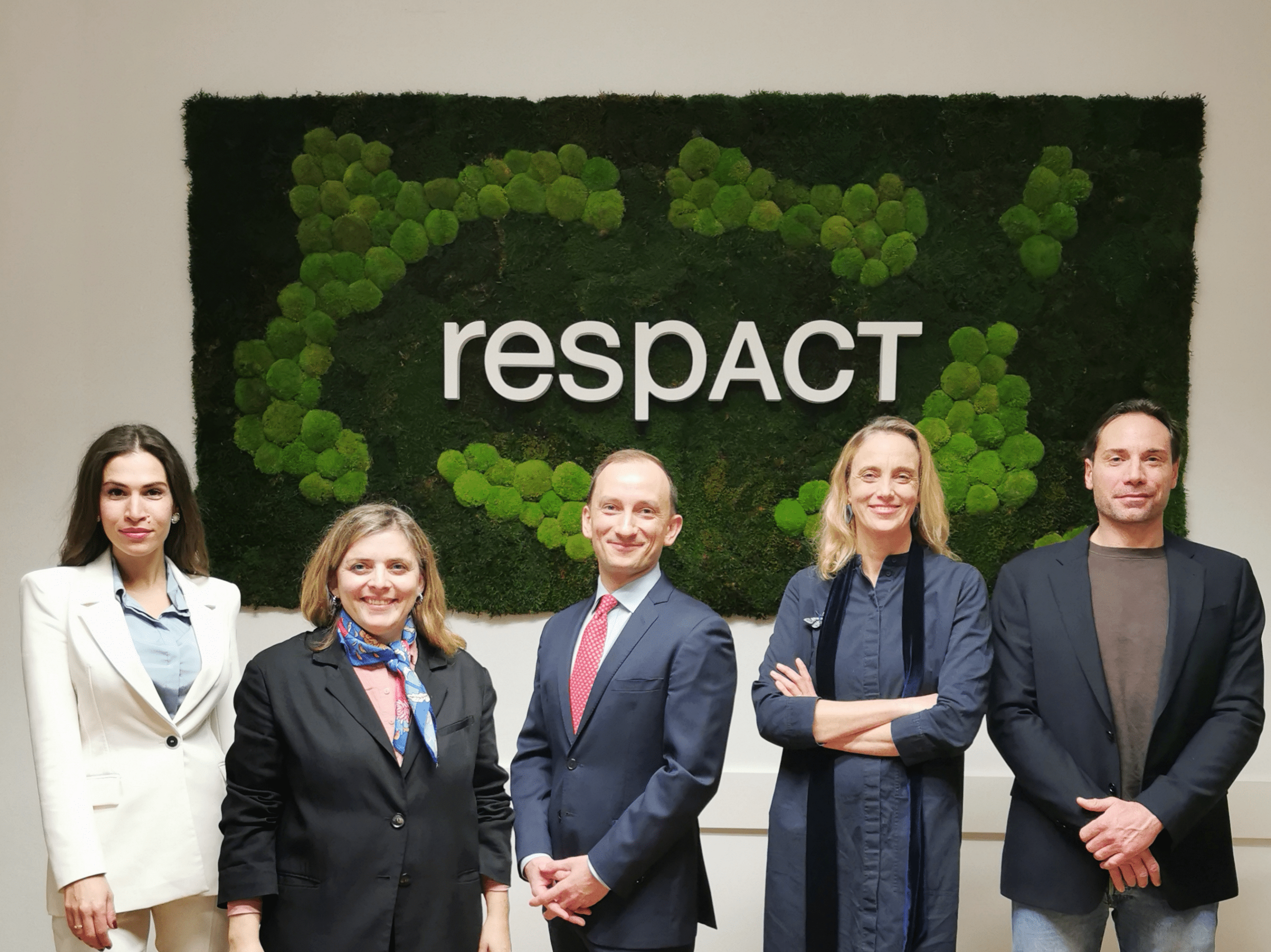 Gruppenbild mit fünf Personen vor einem grünen Hintergrund mit dem respACT-Logo.